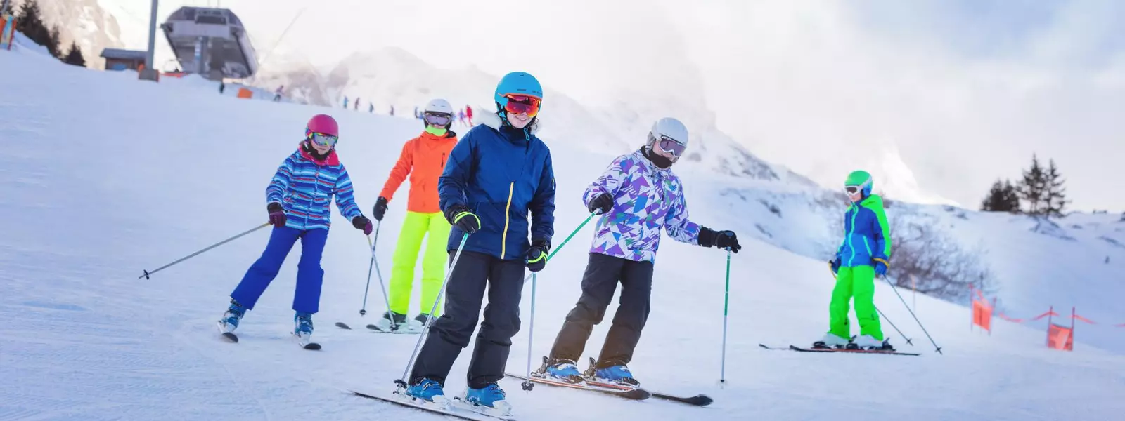 Group of children ski downhill together in colorful outfit on Alpine mountain slope